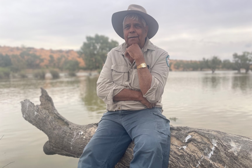 Ranger Don Rowlands sits on a log on the bank of Eyre Creek