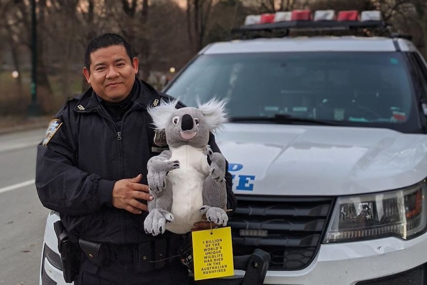 A man in a police uniform holds a stuffed koala
