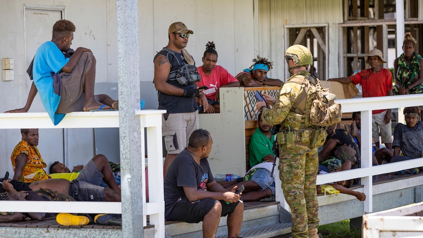 An Australian Army soldier talks with local citizens during a community engagement patrol through Honiara