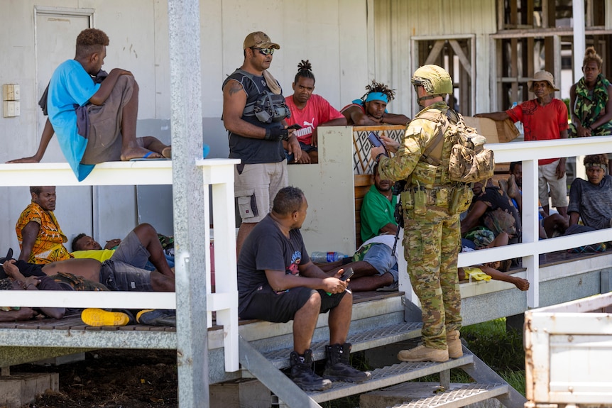 An Australian Army soldier talks with local citizens during a community engagement patrol through Honiara