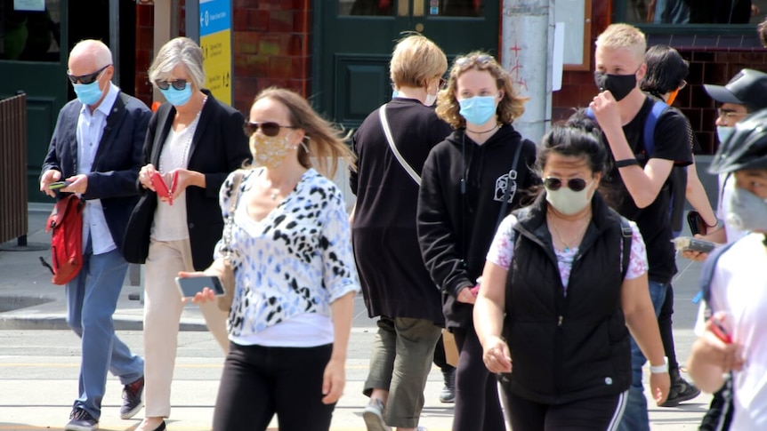 A photo of people wearing masks crossing a street in Melbourne.