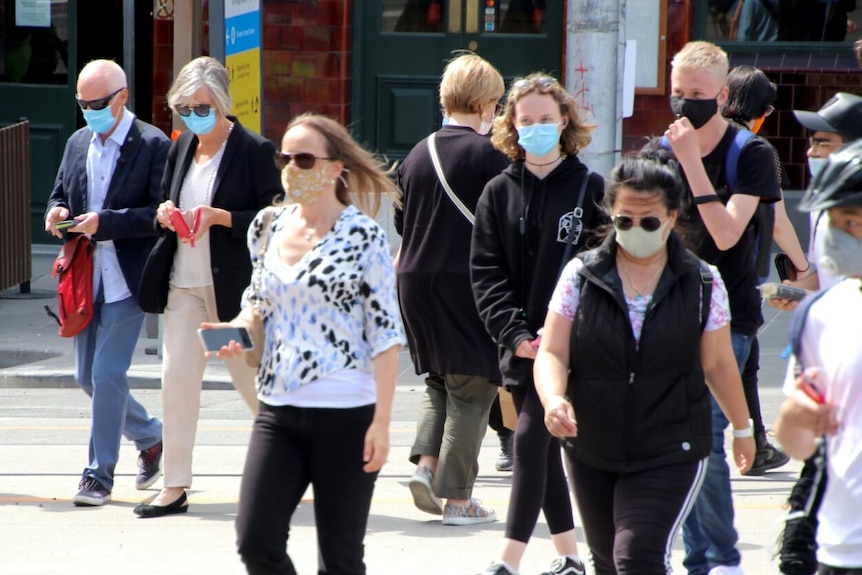 A photo of people wearing masks crossing a street in Melbourne.