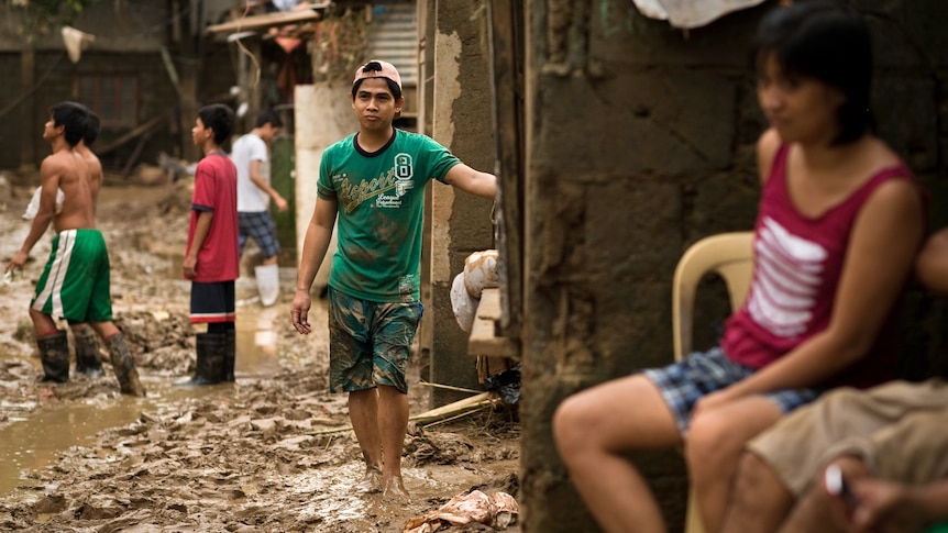 Local residents clean up from the mud left by the floods at a slum east of Manila.