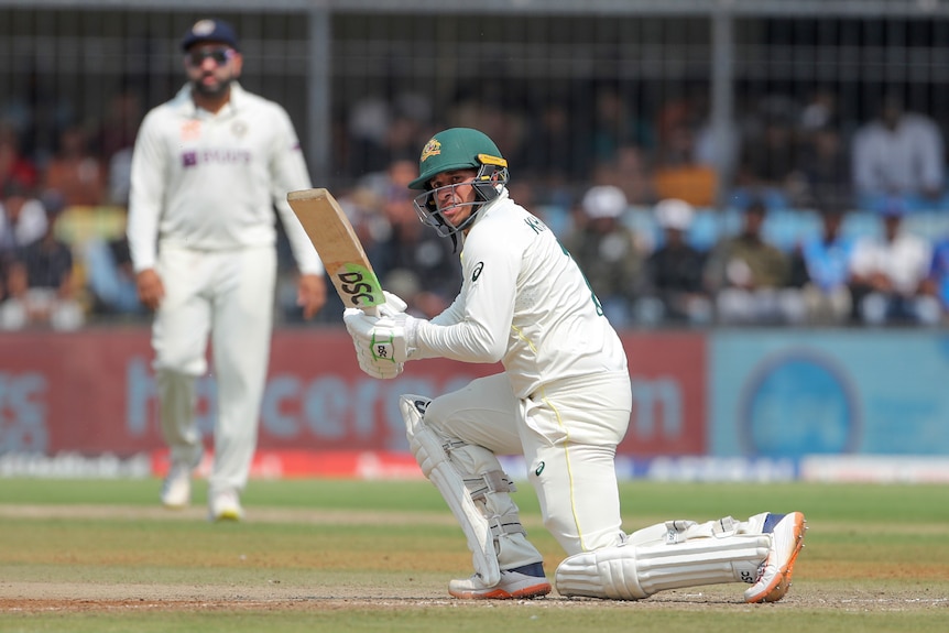 Usman Khawaja looks behind him while kneeling