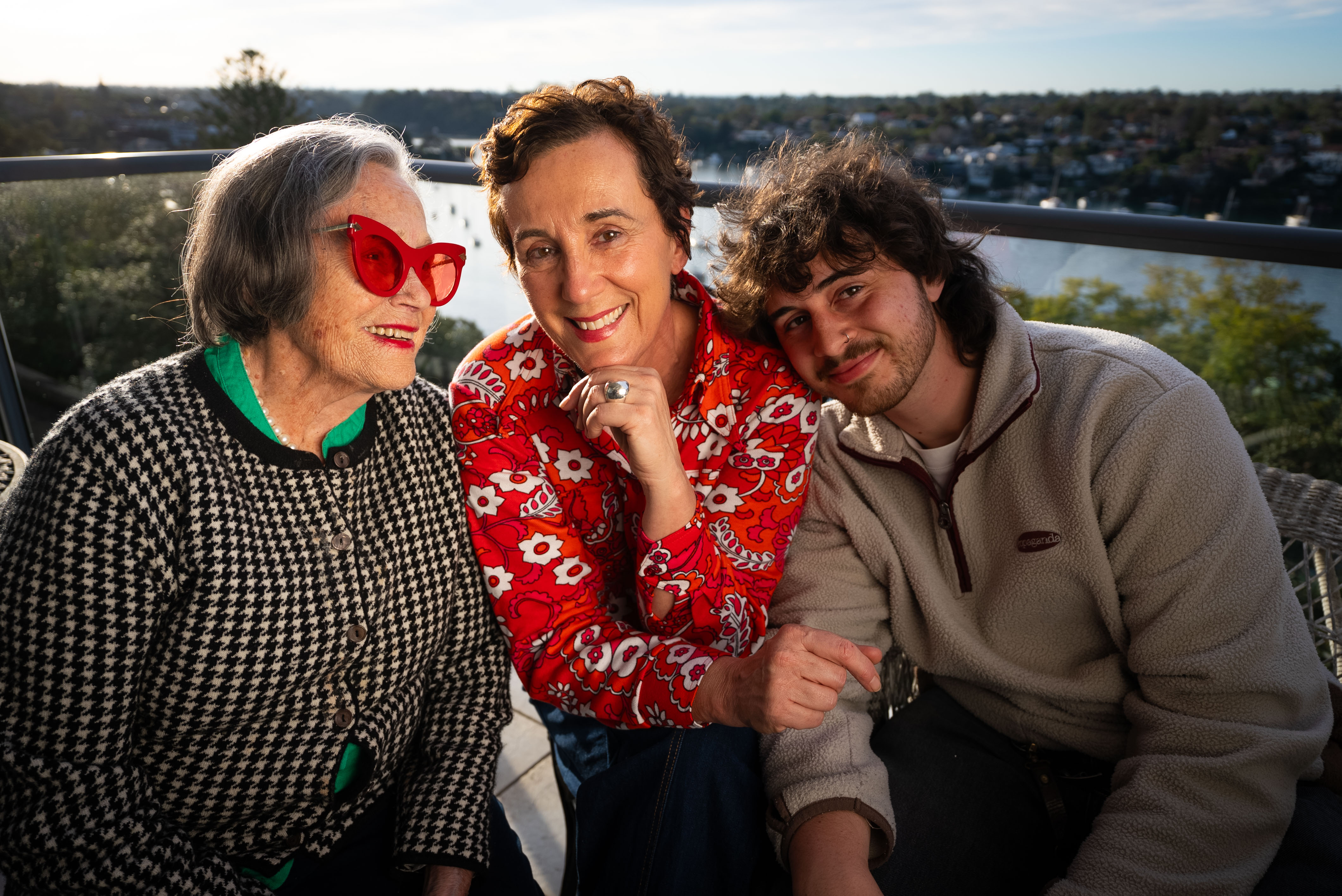 An elderly woman, a middle aged woman and a twenty somethng man smile for a family photo