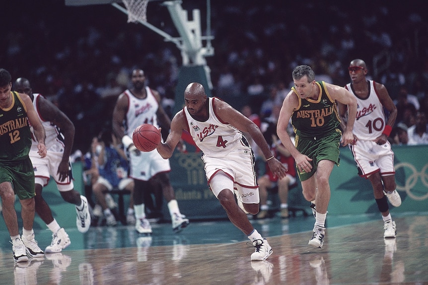 USA's Charles Barkley dribbles away from Australia's Andrew Gaze during a basketball game at the Atlanta Olympics.