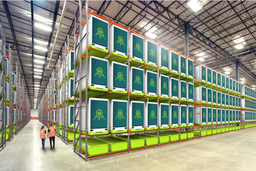 Large green cubes stacked on to of each other in a huge warehouse