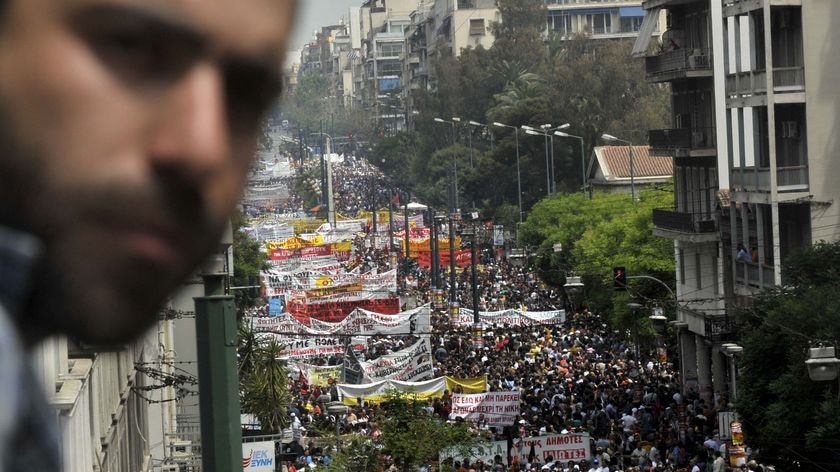 A man looks at thousands of demonstrators marching through the Greek capital of Athens
