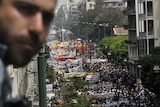 A man looks at thousands of demonstrators marching through the Greek capital of Athens