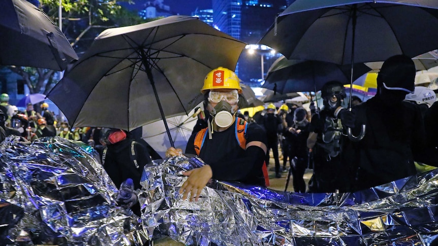 Anti-government protesters hold aluminium foil to prevent the police's blue-colored water cannon in Hong Kong