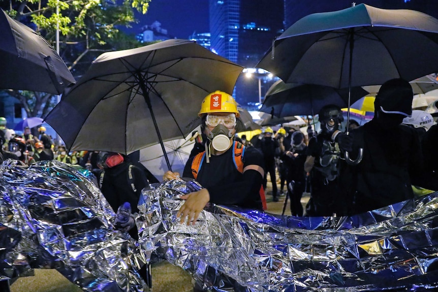 Anti-government protesters hold aluminium foil to prevent the police's blue-colored water cannon in Hong Kong