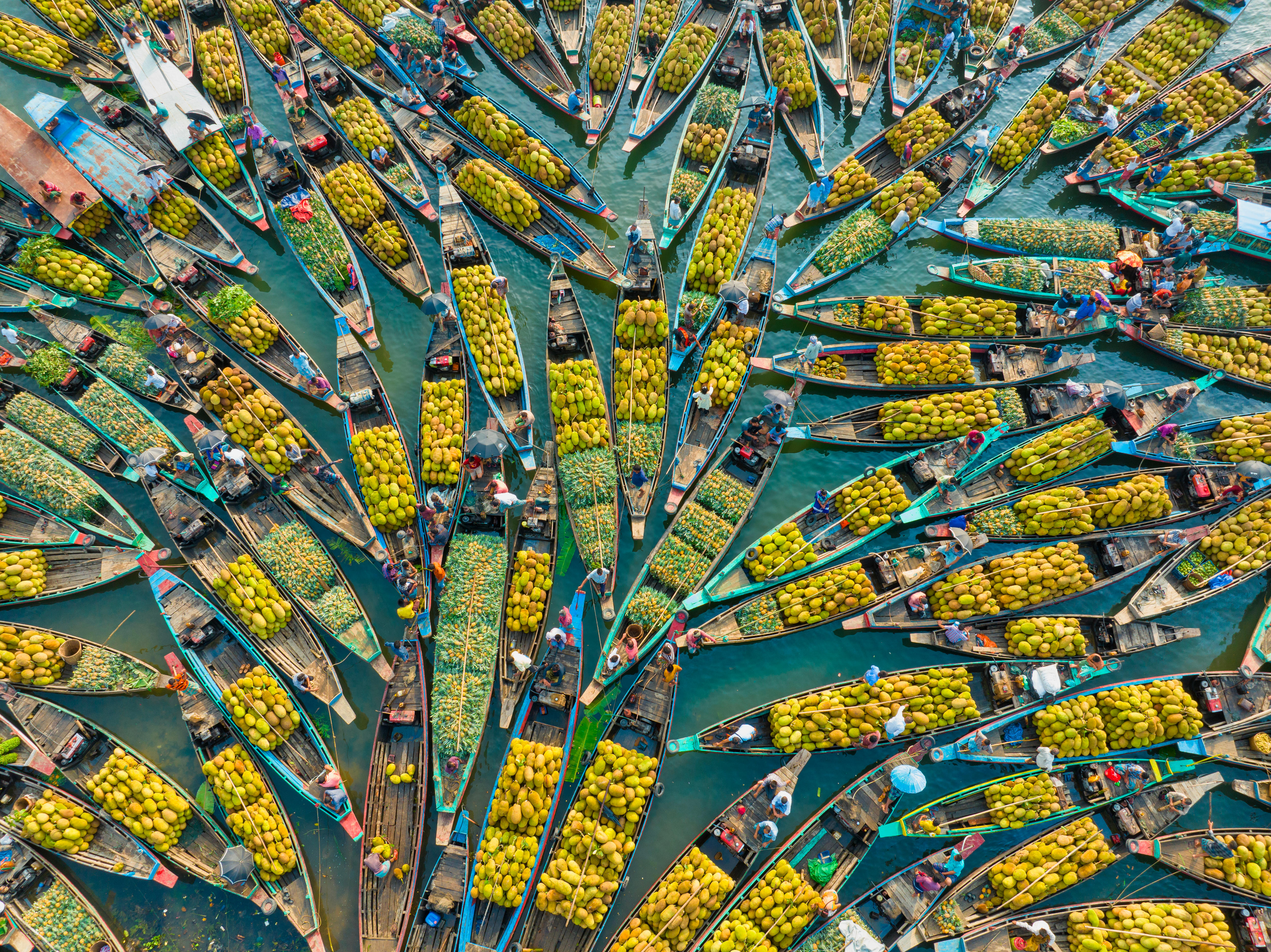 Boats fan out across a stretch of lake, creating a floating market, selling an array of fresh fruit. 