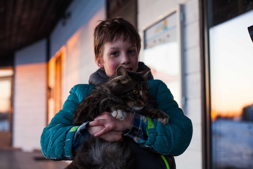 A little boy holds his cat for a story about what to do when the family pet dies.