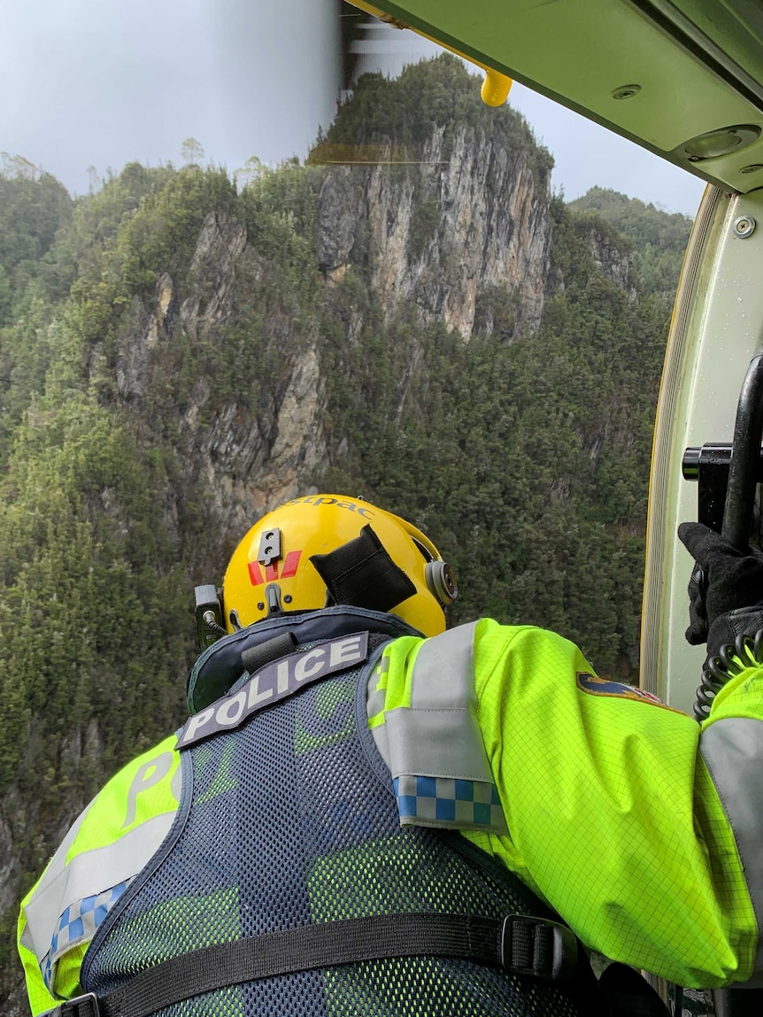 Member of Tasmania's Westpac Rescue Helicopter leaning outside of the aircraft, during the rescue of a 61-year-old woman from Tasmania's north-west's Great Ravine rapids area
