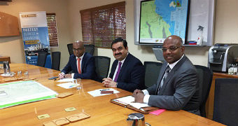 Adani Group chairman Gautam Adani (centre) is flanked by two executives at a board meeting table.