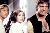 A still from the Star Wars Episode IV, featuring a close-up Luke Skywalker, Princess Leia and Han Solo creeping down a corridor.