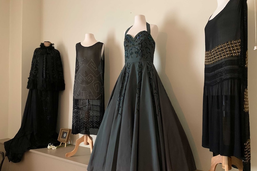Four black historic gowns from different eras.