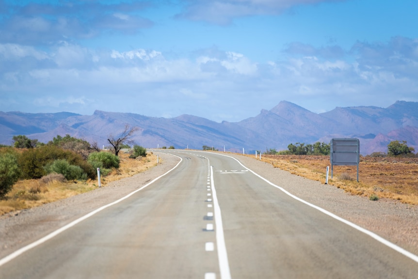 A road recedes into the distance with the Flinders Ranges in the background.