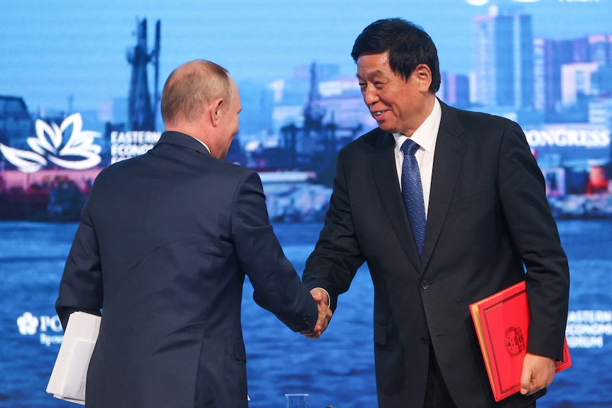 Владимир Путин обменивается рукопожатием с Ли Чжаньшу.