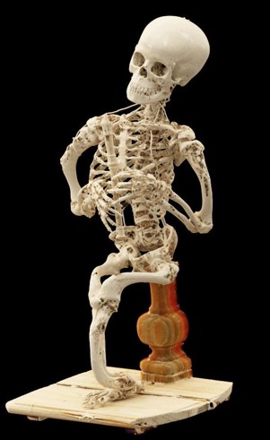 A seated skeleton holding a wooden recorder.