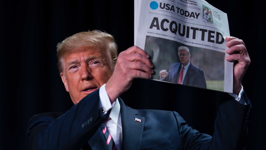 Trump stares straight at the camera holding a USA Today newspaper with the headline "ACQUITTED".