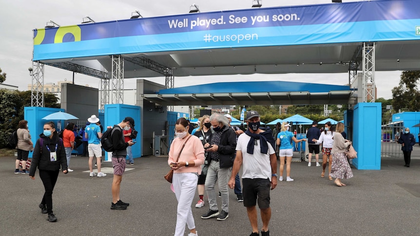 People wearing masks check their mobile phones after passing through gates at the Australian Open.