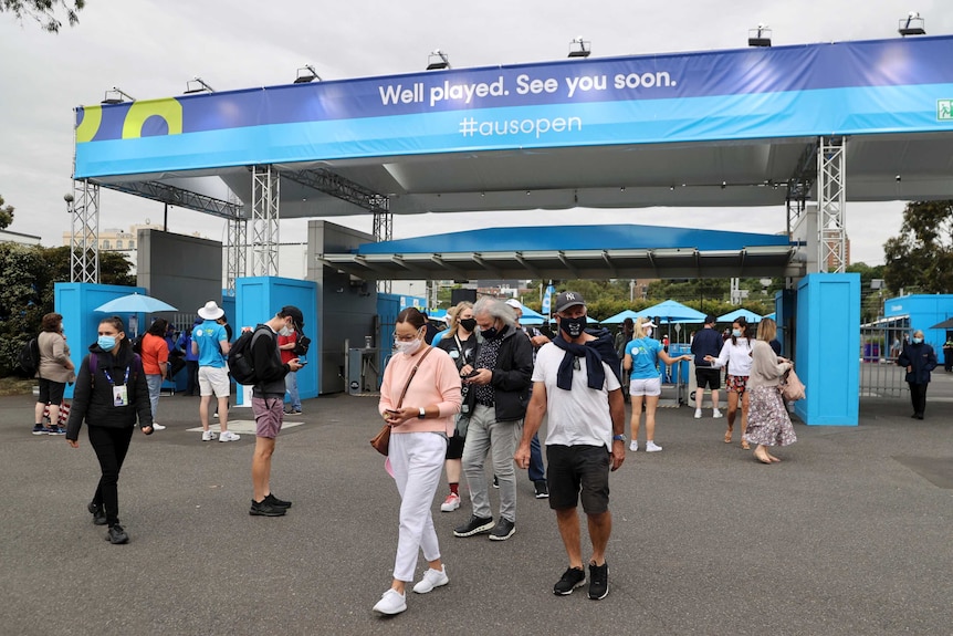 People wearing masks check their mobile phones after passing through gates at the Australian Open.