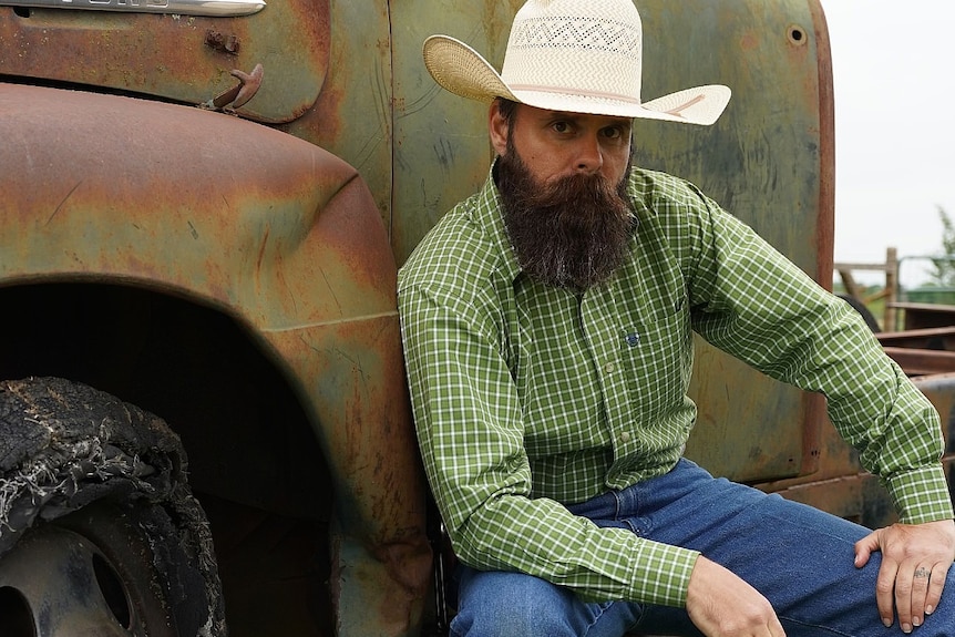 Brian Firebaugh poses next to an old pick up truck at his ranch