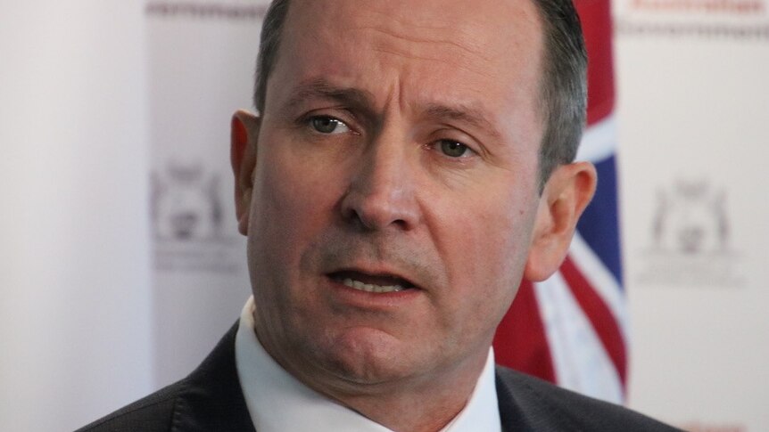 Mark McGowan talks in front of a flag and a WA Government sign.