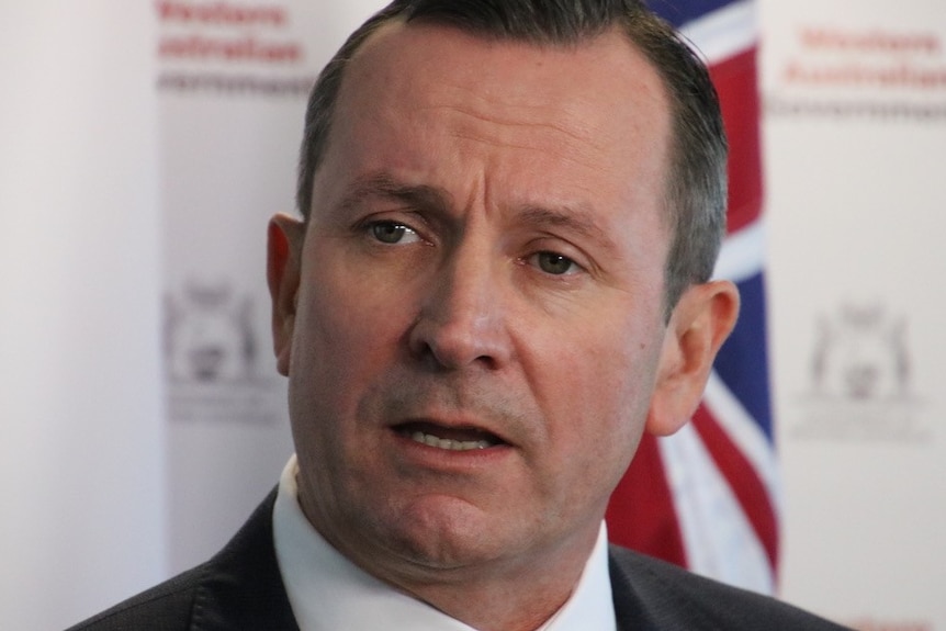 Mark McGowan talks in front of a flag and a WA Government sign.