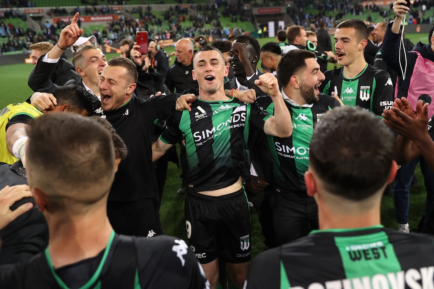 Western United A-League Men players stand arm in arm and shout in joy after winning the grand final.