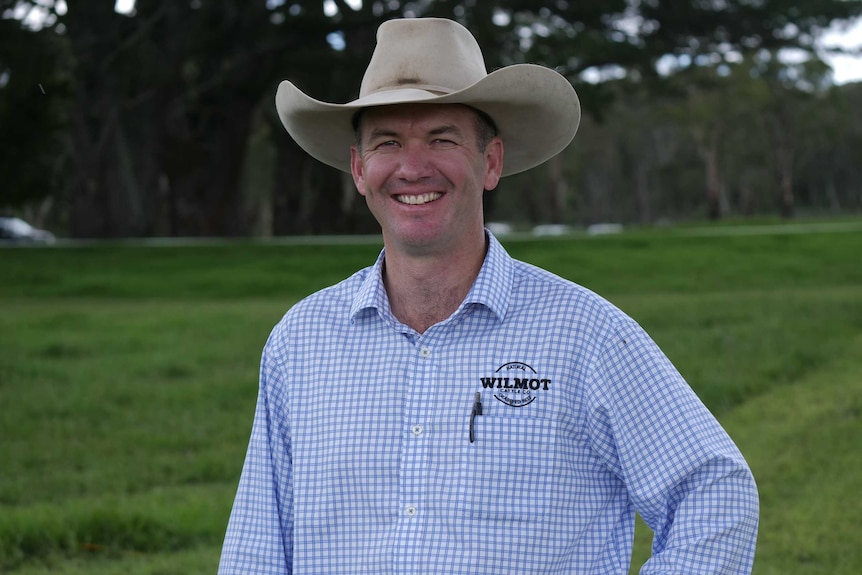 A farmer in a wide-brimmed hat smiles for the camera