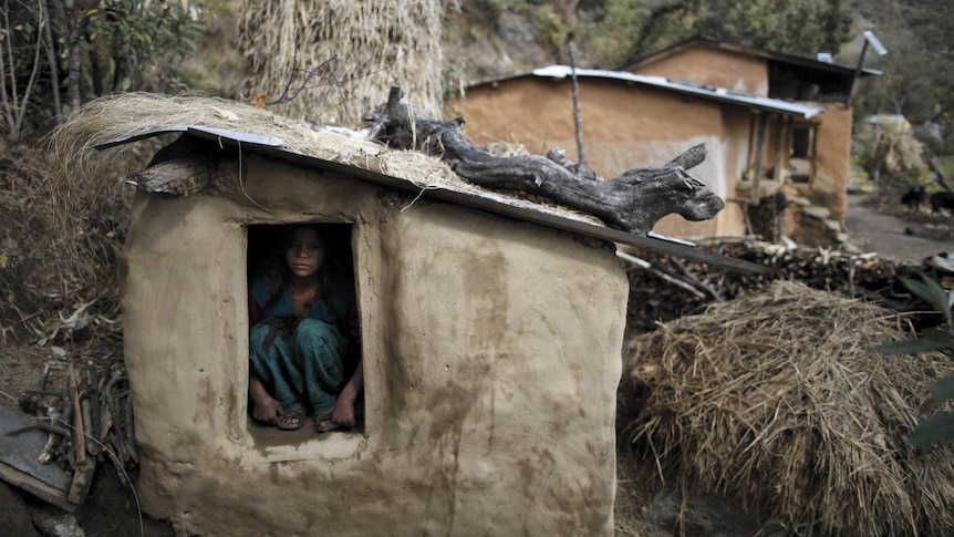 Young girl crouched in a shed