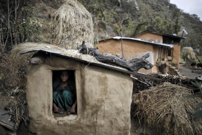 Young girl crouched in a shed