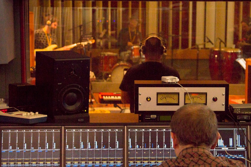 A band plays in a radio studio, control desk in foreground.