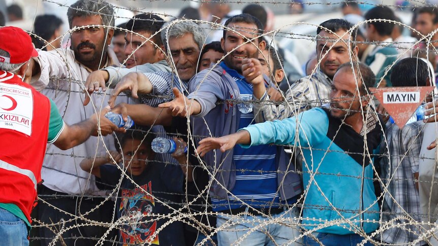 Men reach for water bottles on Turkey-Syria border