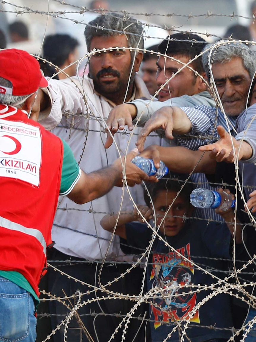 Men reach for water bottles on Turkey-Syria border