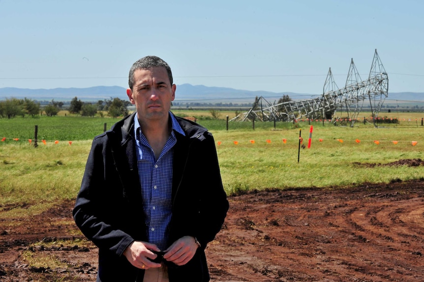 South Australia Energy Minister Tom Koutsantonis stands in front of a fallen transmission tower.