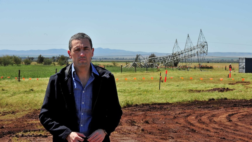 South Australia Energy Minister Tom Koutsantonis stands in front of a fallen transmission tower.