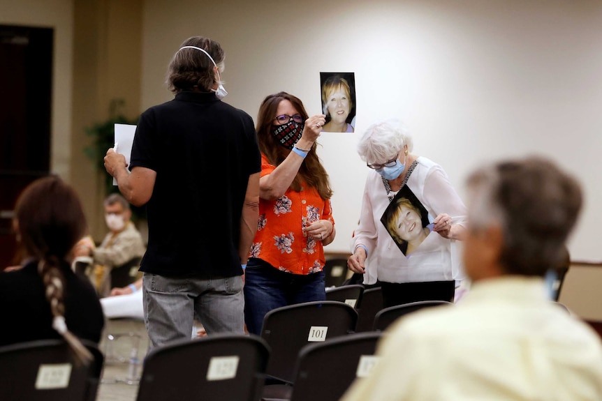 Three people in face masks hold up photos of a woman in court