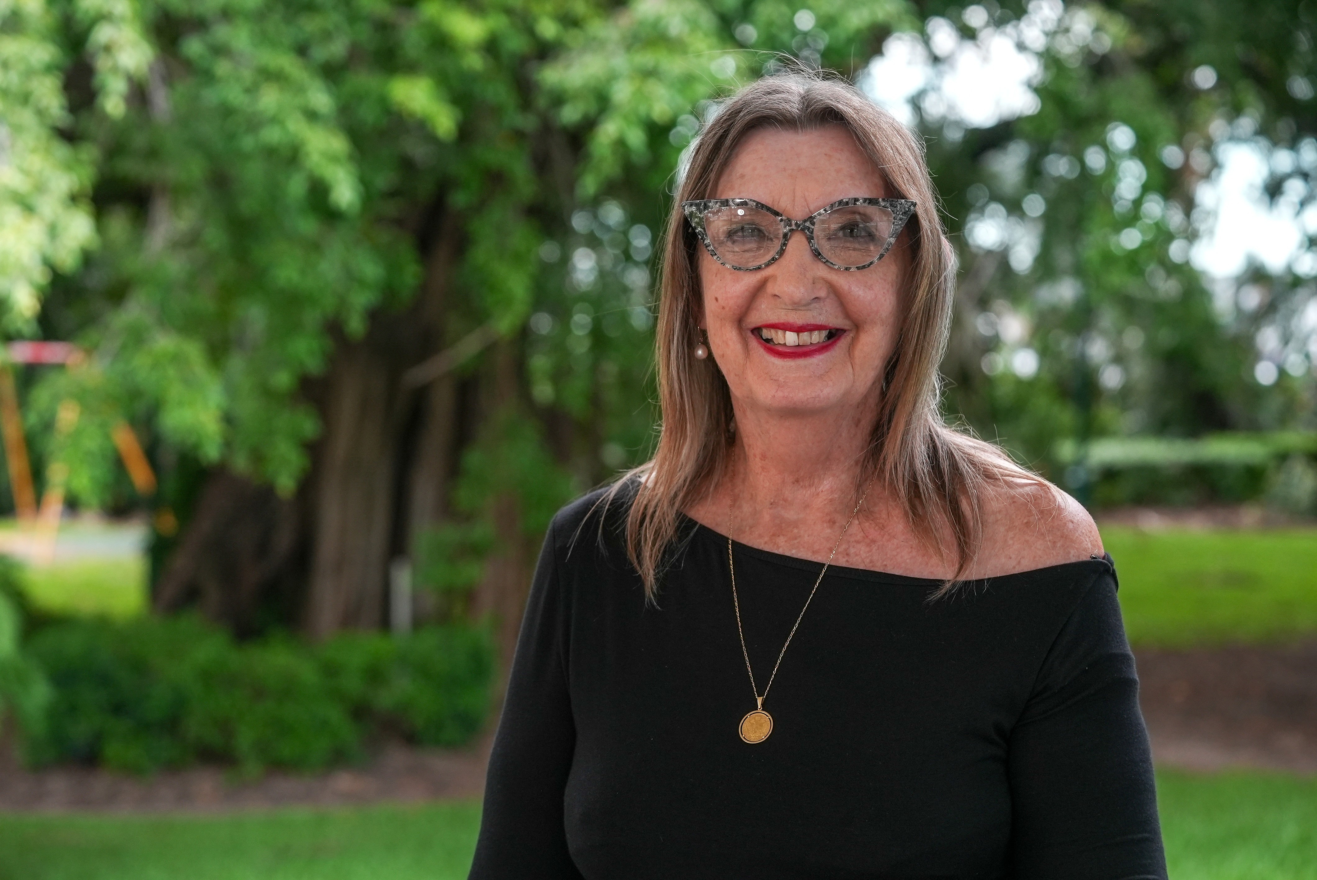 Una mujer con el pelo hasta los hombros y gafas sonríe a la cámara.