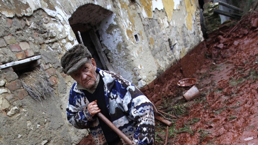 An elderly man tries to clean up his home in the village of Devecser
