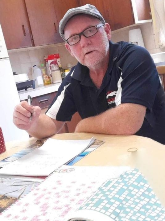 A man in a hat with glasses doing a puzzle