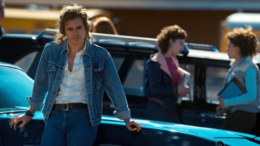 Australian actor Dacre Montgomery, as Billy, stands against a car