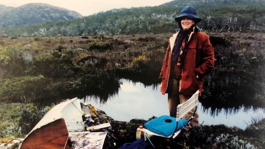 Photograph of a woman in the wilderness, with her painting equipment