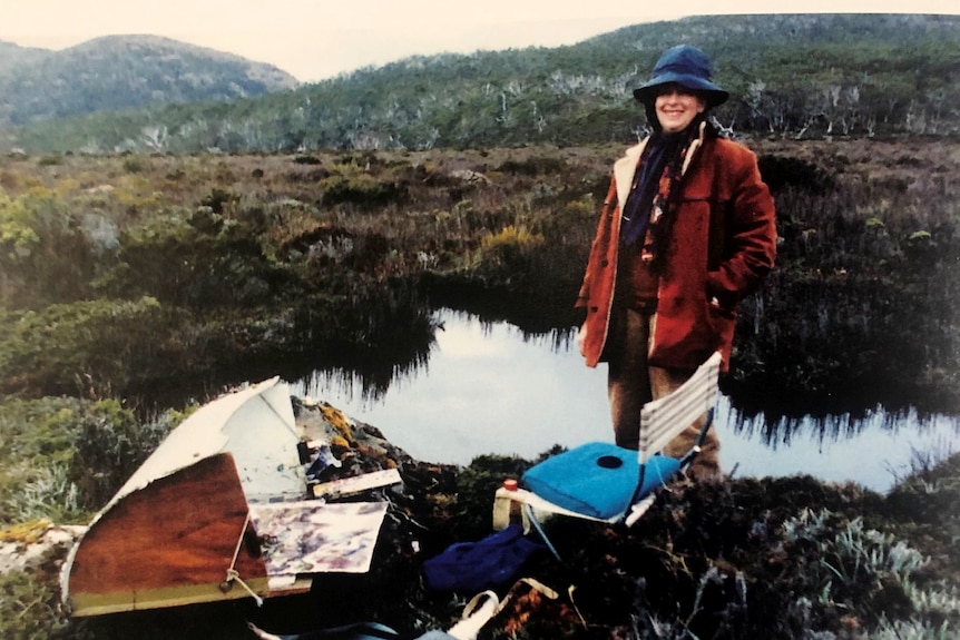 Photograph of a woman in the wilderness, with her painting equipment