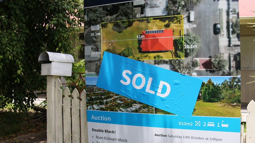Sold sign next to letterbox and fence of Queenslander-style house.