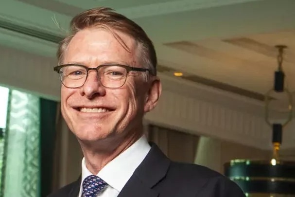 A man in a suit smiles at the camera.