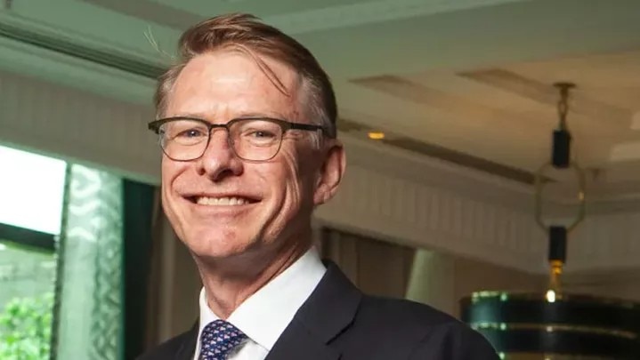 A man in a suit smiles at the camera.