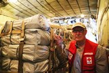 A humanitarian worker stands beside aid bound for Vanuatu.